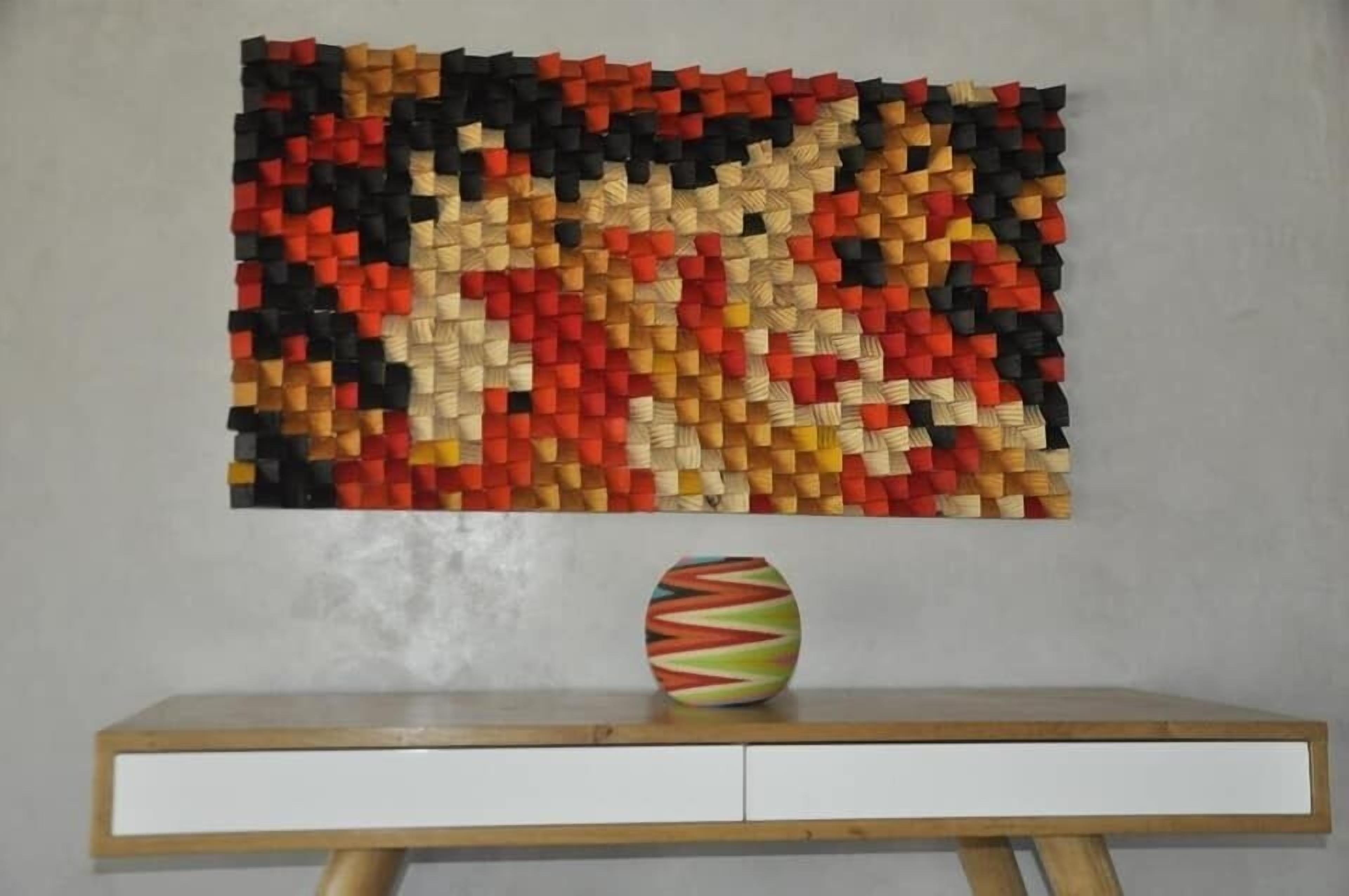 Una obra d'art mural feta amb blocs de colors i un ram d'un vas sobre una taula de fusta.