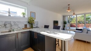 A modern kitchen with dark cabinets, a marble countertop, and a large window overlooking a deck. - Cooleens- Chic 1-bedroom Apt. in North Berwick (North Berwick)