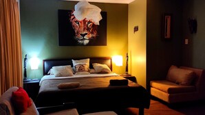 Une chambre d’hôtel avec un grand lit, deux lampes de chevet, un canapé et un fauteuil.