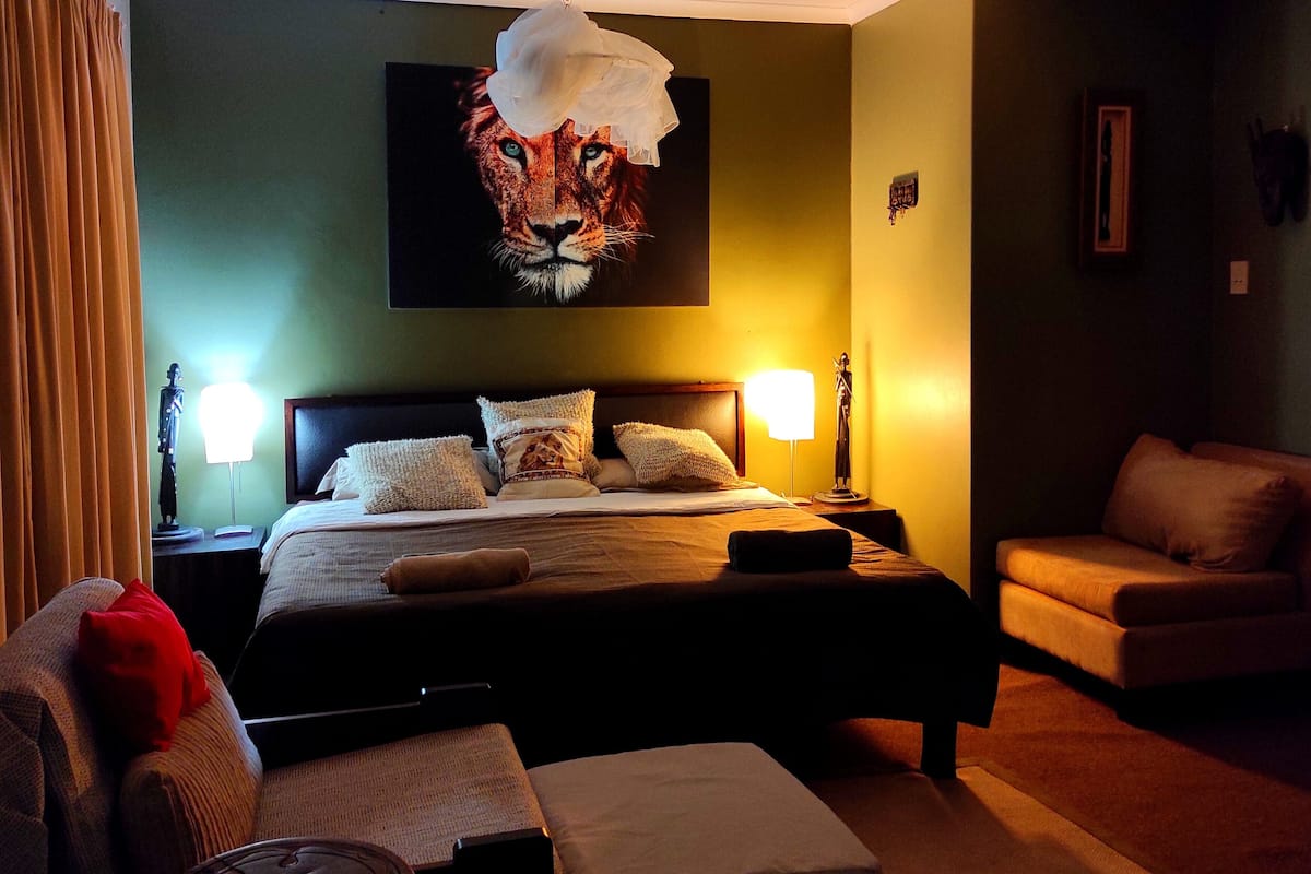 Ein Hotelzimmer mit einem großen Bett, zwei Nachttischlampen, einer Couch und einem Sessel.