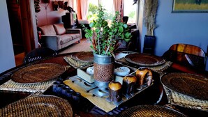 Un espace repas agrémenté d’une plante centrale, de sets de table en fibres tressées et d’une variété de plats.