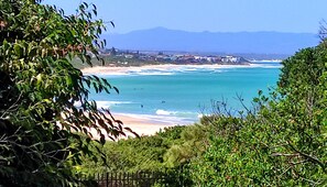 Un paysage côtier avec une plage, l’océan et des montagnes à l’horizon.