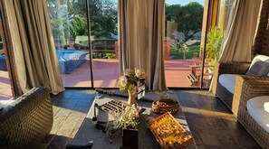 Une pièce dotée d'une grande fenêtre, de meubles en osier, d'un vase décoratif et donnant sur un jardin.