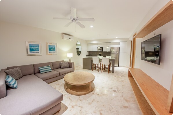 A modern living room with a sofa, a round coffee table, and a TV mounted on the wall.