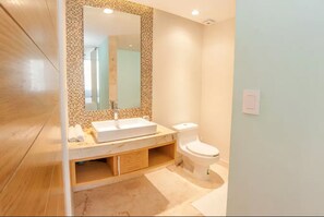 A bathroom with a white sink, a mirror, and a toilet.