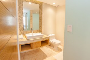 A modern bathroom with a large mirror, a white sink, and a toilet.