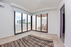 Una habitación amplia con grandes puertas corredizas de vidrio que dan a un patio exterior.