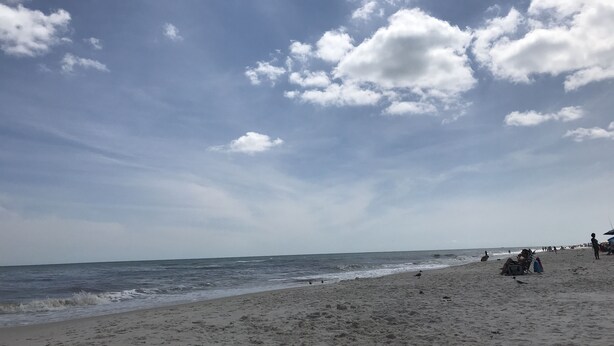 Una playa con cielo despejado y algunas nubes.