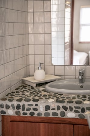 Une salle de bain avec un comptoir à motifs de pierre, un lavabo blanc et un miroir.