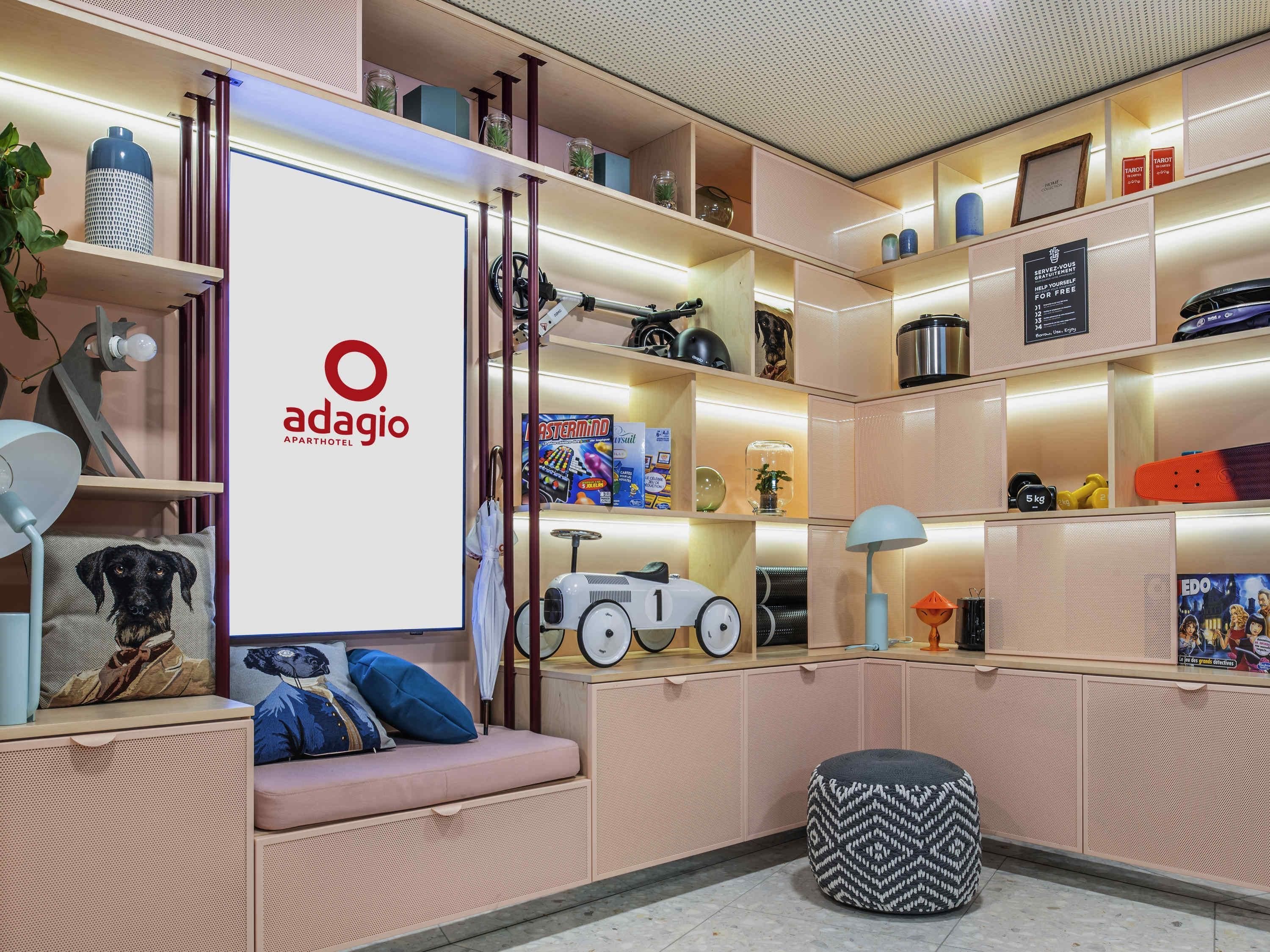 Een moderne woonkamer met een bank, voetenbankje en een grote tv-scherm waarop het Adagio-logo wordt getoond.