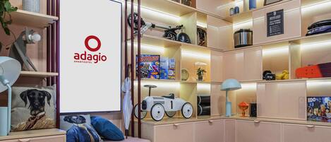 A modern living room with a sofa, ottoman, and a large TV screen displaying the adagio logo.