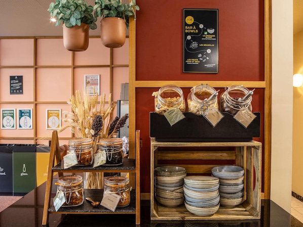 A buffet area with a variety of food options, including jars of granola and nuts, and a selection of bowls and plates.