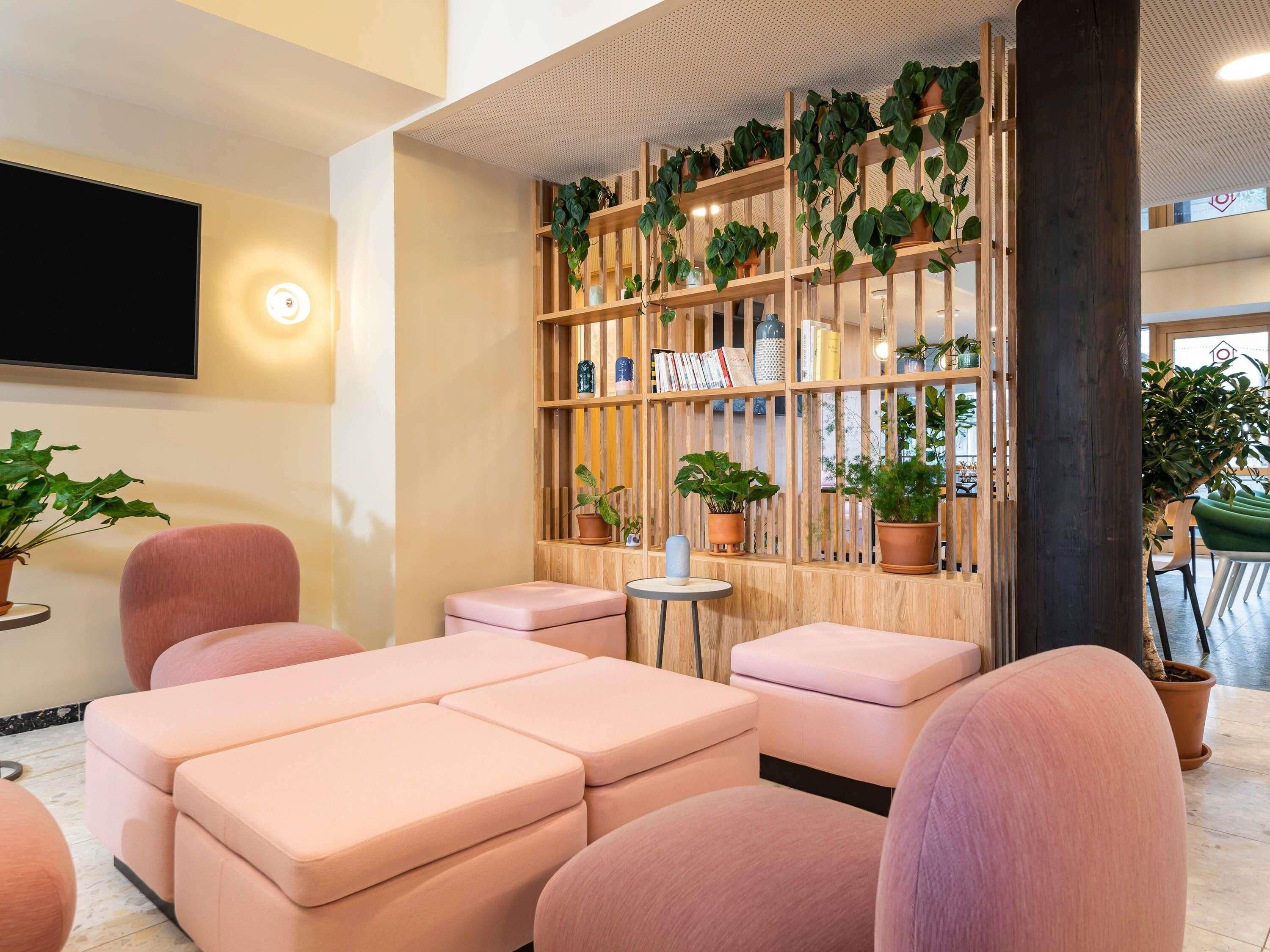 Un área de lounge moderna con asientos acolchados, una pared verde de madera y un televisor de pantalla plana.