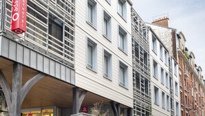 Un edificio moderno con varias ventanas y un llamativo letrero rojo del hotel Adagio.