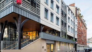 A modern hotel with a prominent red sign, a covered entrance, and a staircase leading to the lobby. - Aparthotel Adagio Paris Nation (Paris)