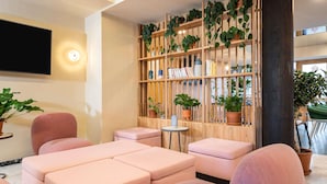 A modern lounge area with cushioned seating, a wooden plant wall, and a flat-screen TV. - Aparthotel Adagio Paris Nation (Paris)