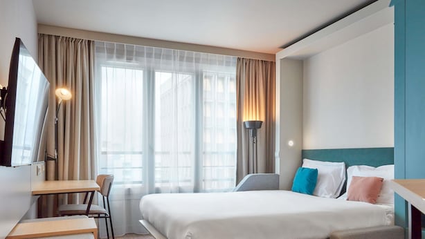 A modern hotel room with a bed, desk, chair, and a TV. - Aparthotel Adagio Paris Nation (Paris)