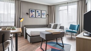 A modern hotel room with a bed, a desk, a chair, and a TV. - Aparthotel Adagio Paris Nation (Paris)