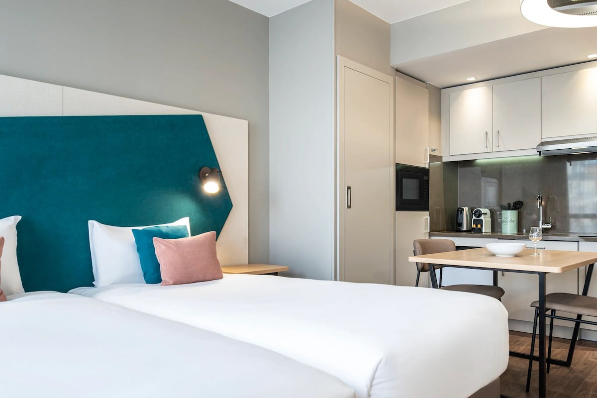 Una habitación de hotel con una cama, un escritorio y un espacio para preparar comidas.