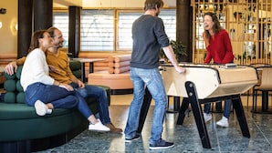 A pool table in a modern indoor setting with seating areas and a plant display. - Aparthotel Adagio Paris Nation (Paris)