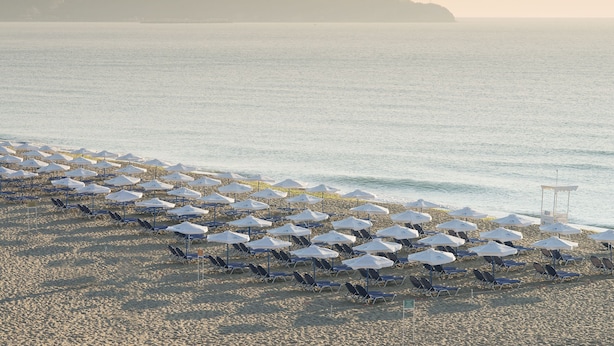 Een strand met rijen parasols en ligstoelen.