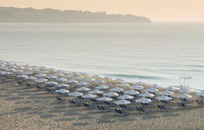A beach with rows of sun umbrellas and lounge chairs. - Sunrise All Suites Resort - All Inclusive (Obzor)