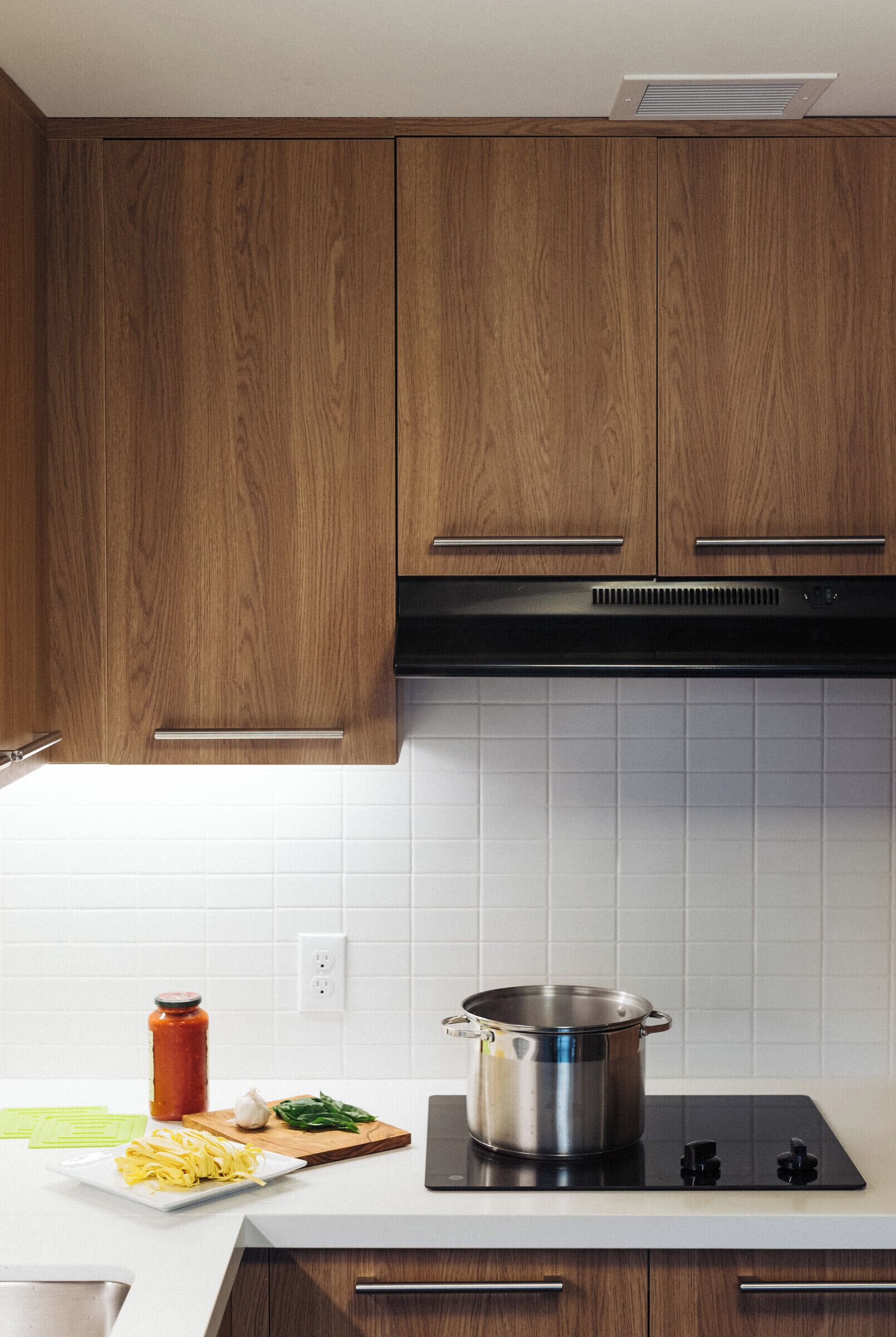 A modern kitchen with wooden cabinets, a black stove, and a white tiled backsplash.