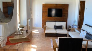 A living room with a wooden ceiling, a TV mounted on a wooden wall, a sofa, a coffee table, and a chair.