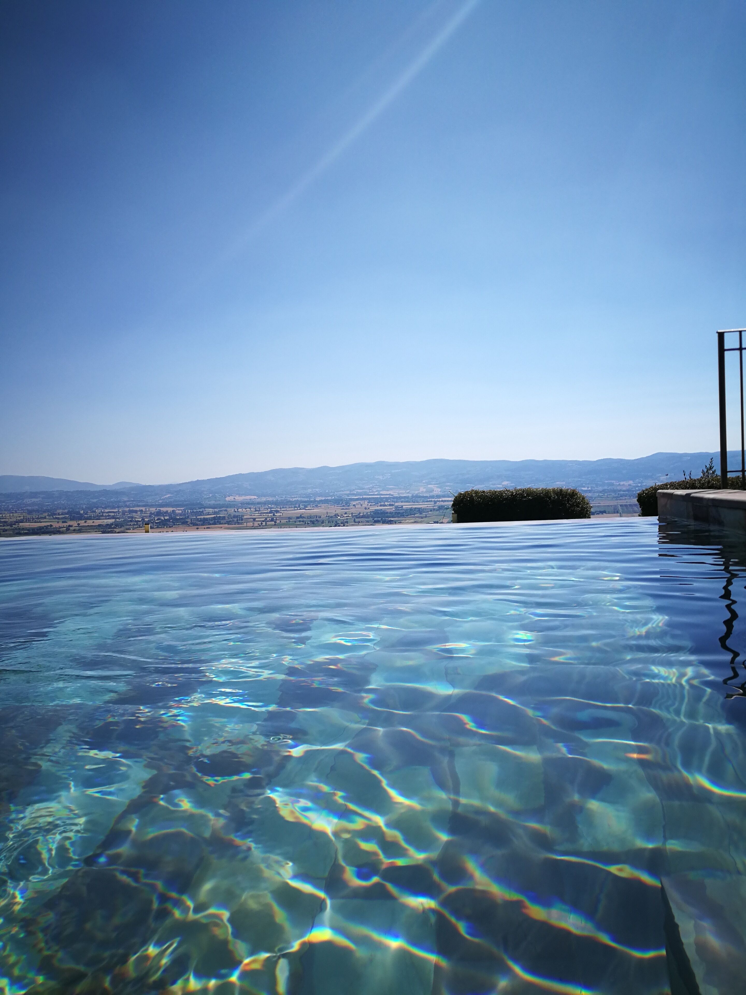 A clear infinity pool with a view of distant mountains and a clear sky.