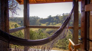 A hammock under a wooden structure with a view of a hilly landscape. - Pousada Cabanas no Mundo (Gonçalves)