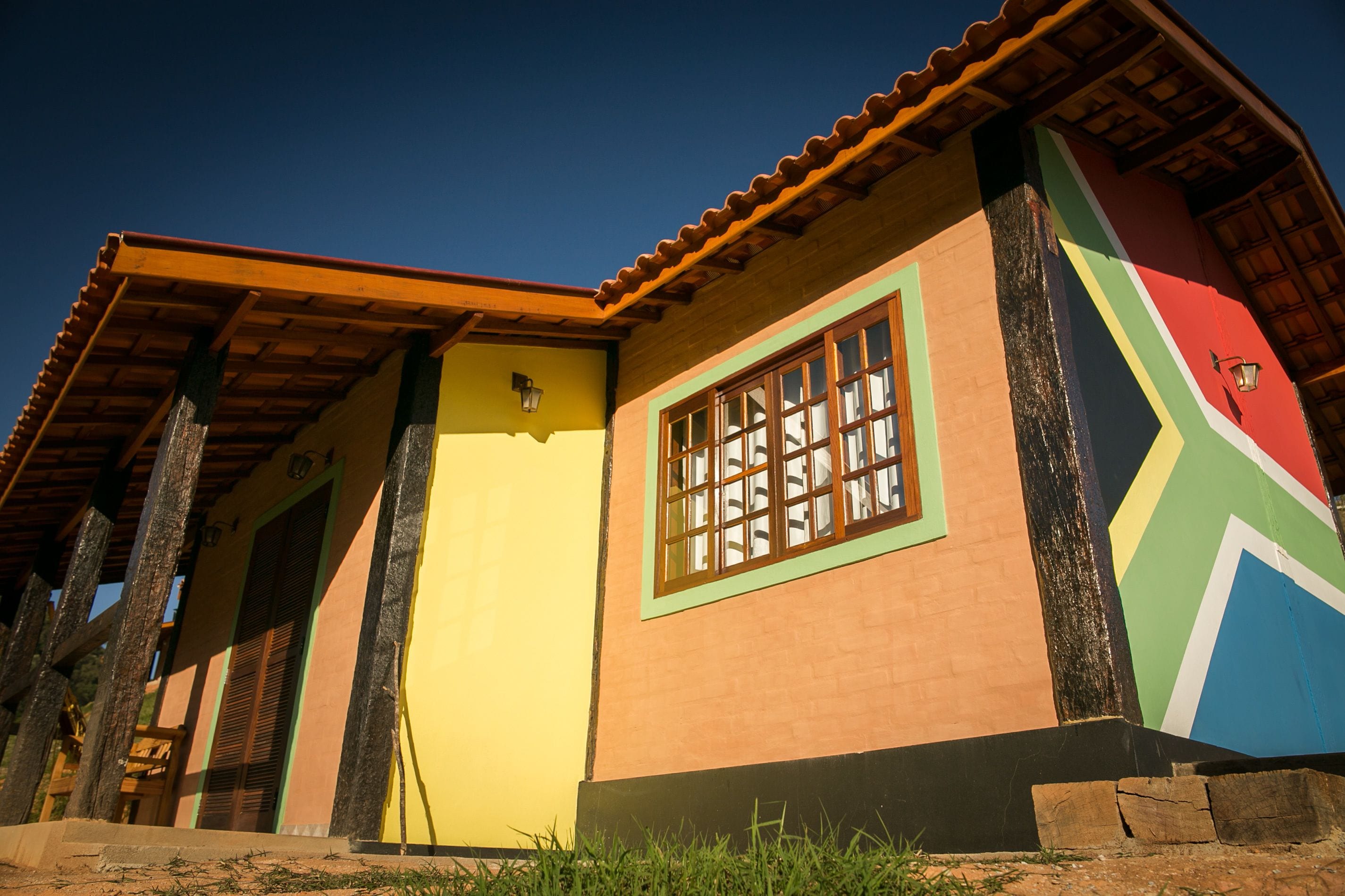 A colorful building with a distinct geometric facade, a visible window with multiple panes, and a wooden roof structure.