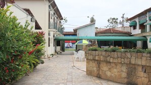 A paved pathway leading to a building with a green awning, stone wall, and potted plants. - Hotel Chalé São Jorge (Aparecida)
