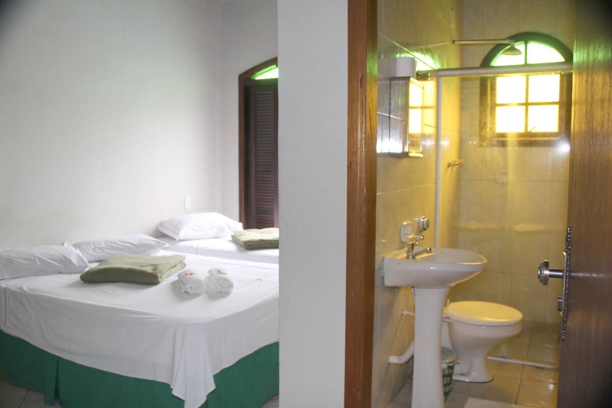 A hotel room with a bed, a bathroom with a sink and toilet, and a shower.