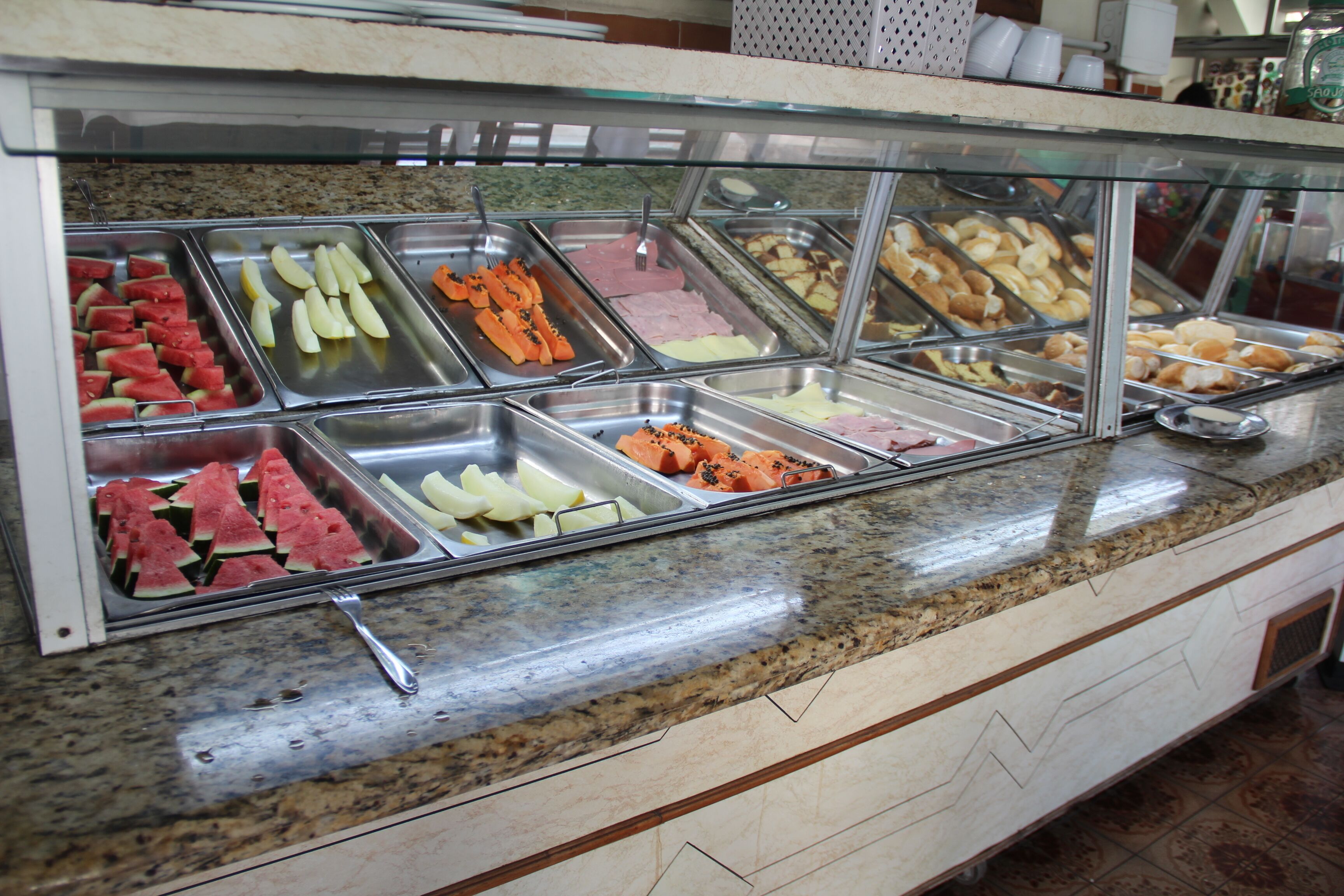 A buffet with various food items including fruits, vegetables, and meats.