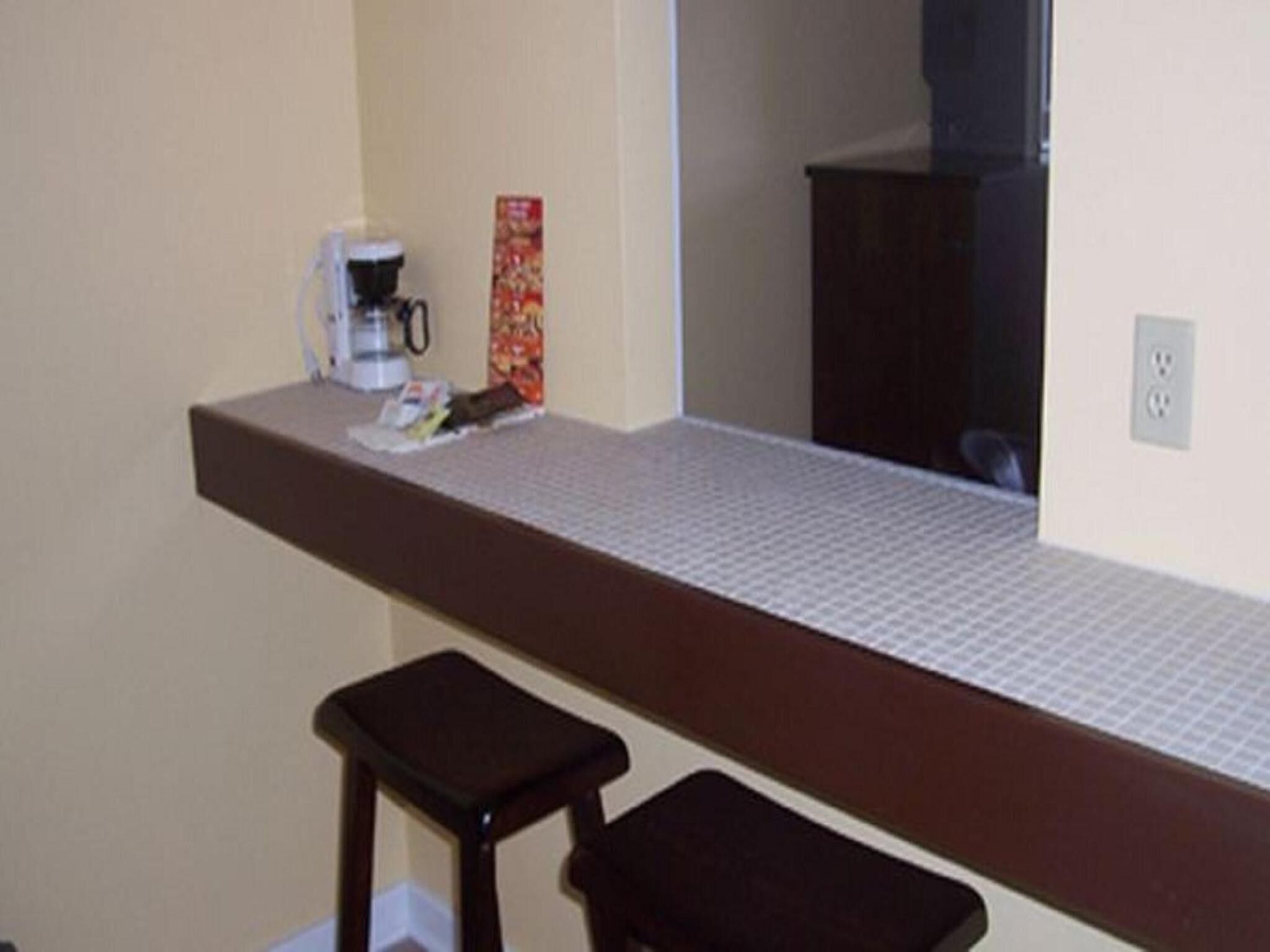 Een kitchenette met een koffiezetapparaat, een klein barkrukje en een magnetron.