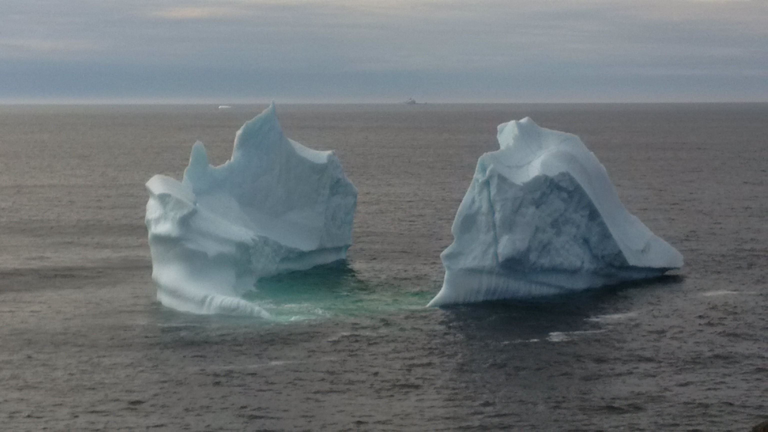 Dos icebergs enormes flotando en aguas tranquilas.