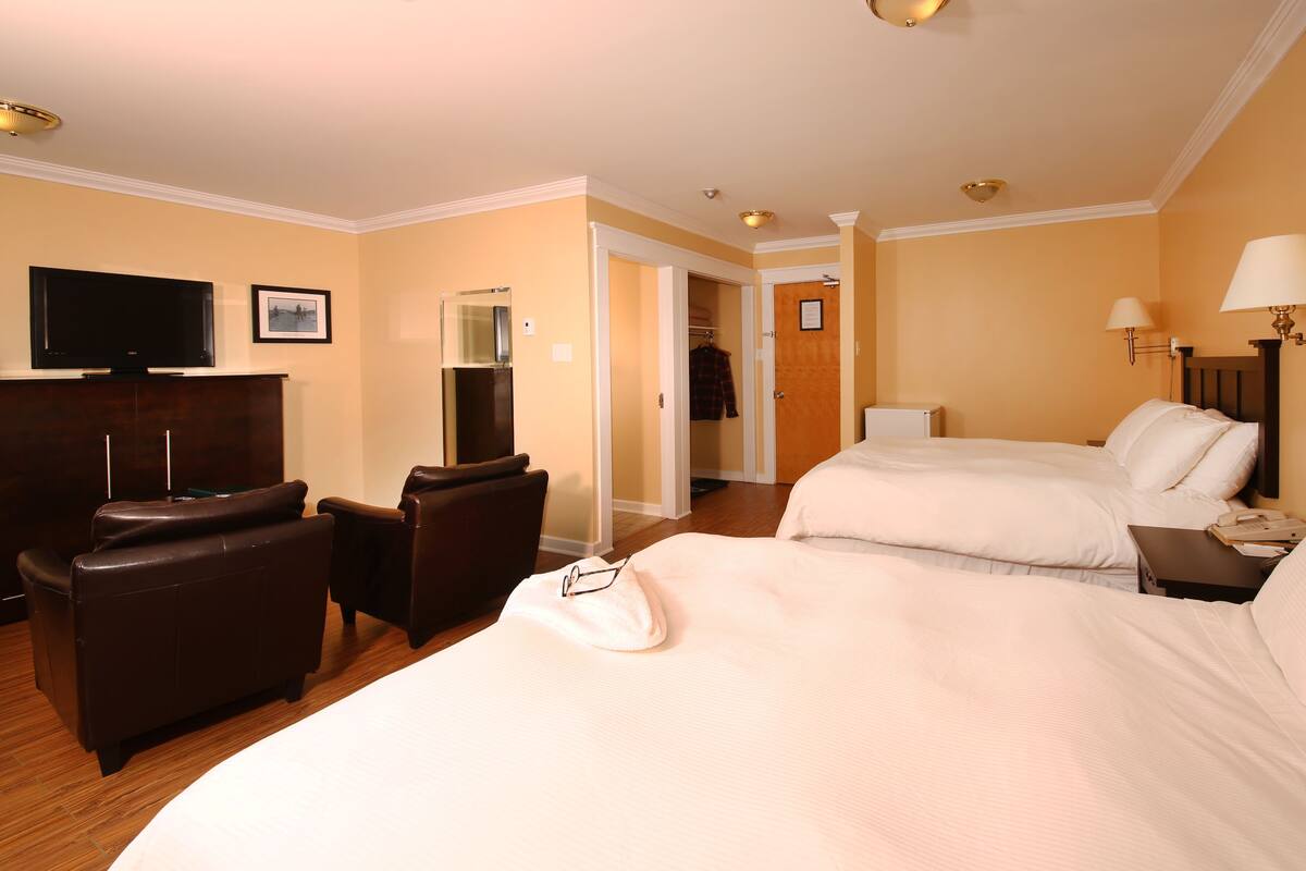 Een hotelkamer met twee bedden, een televisie, een bureau en een stoel.
