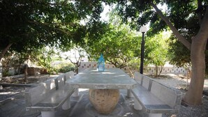 Un banco de piedra con una mesa central, rodeado de árboles y un farol.
