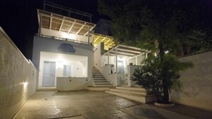 Un edificio moderno con una escalera que conduce a un segundo piso, un área exterior cubierta y una planta en maceta.