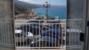 A balcony with a view of the sea, cars parked below, and a lamp post. - b & b in the historic center, with a panoramic terrace, 400 meters from the sea (Pizzo)