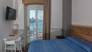 A bedroom with a bed, a desk, a chair, a television, and a view of the sea. - b & b in the historic center, with a panoramic terrace, 400 meters from the sea (Pizzo)