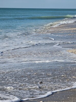 A beach with clear water, pebbles, and a sandy shore.