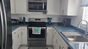 Een moderne keuken met witte kasten, roestvrijstalen apparatuur en een vloerkleed met een blauw patroon.