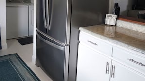 Een moderne keuken met een roestvrijstalen koelkast, witte kasten en een keukeneiland met werkblad.