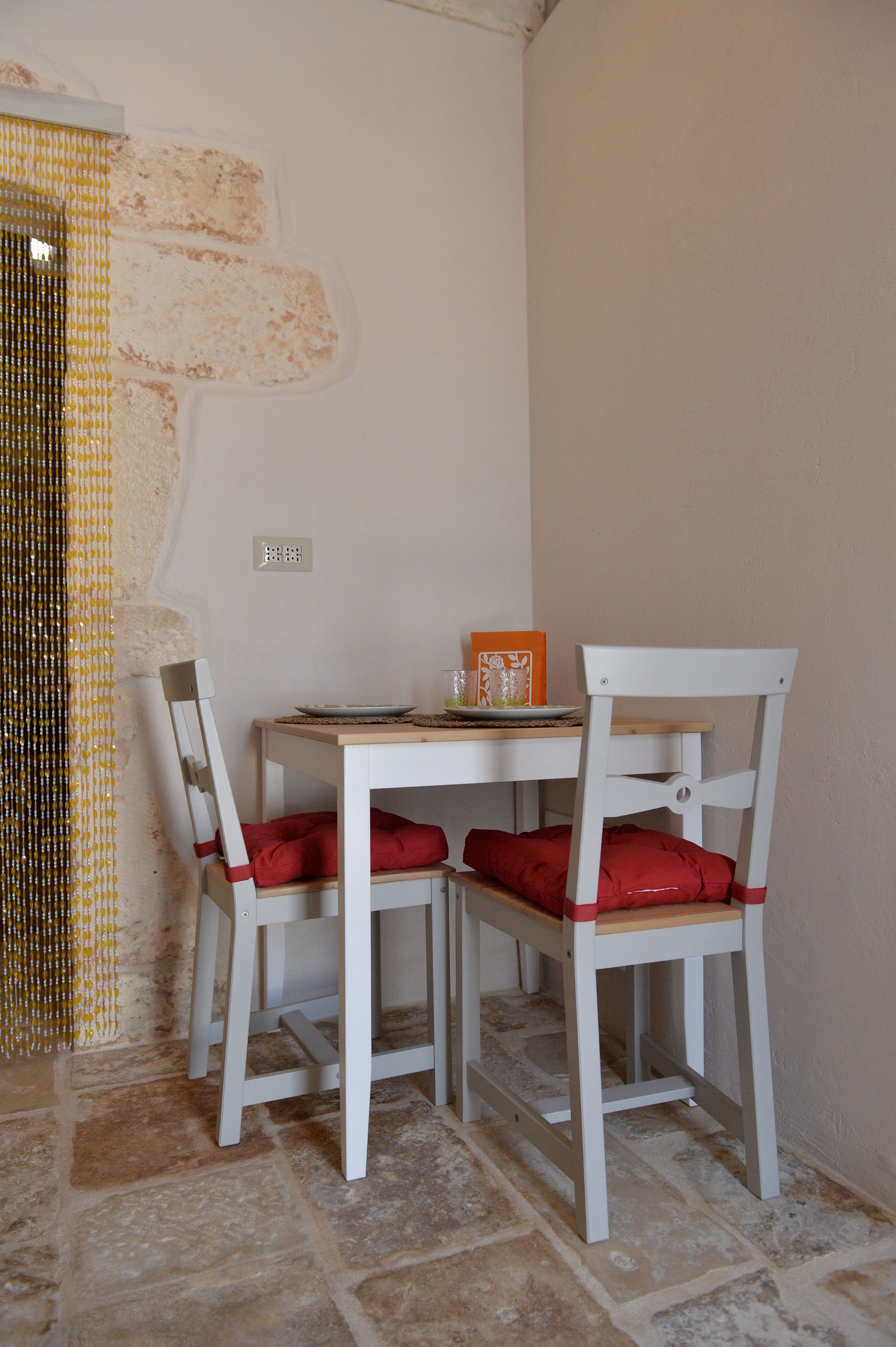 A dining area with two white chairs, a wooden table, and a plate of food.