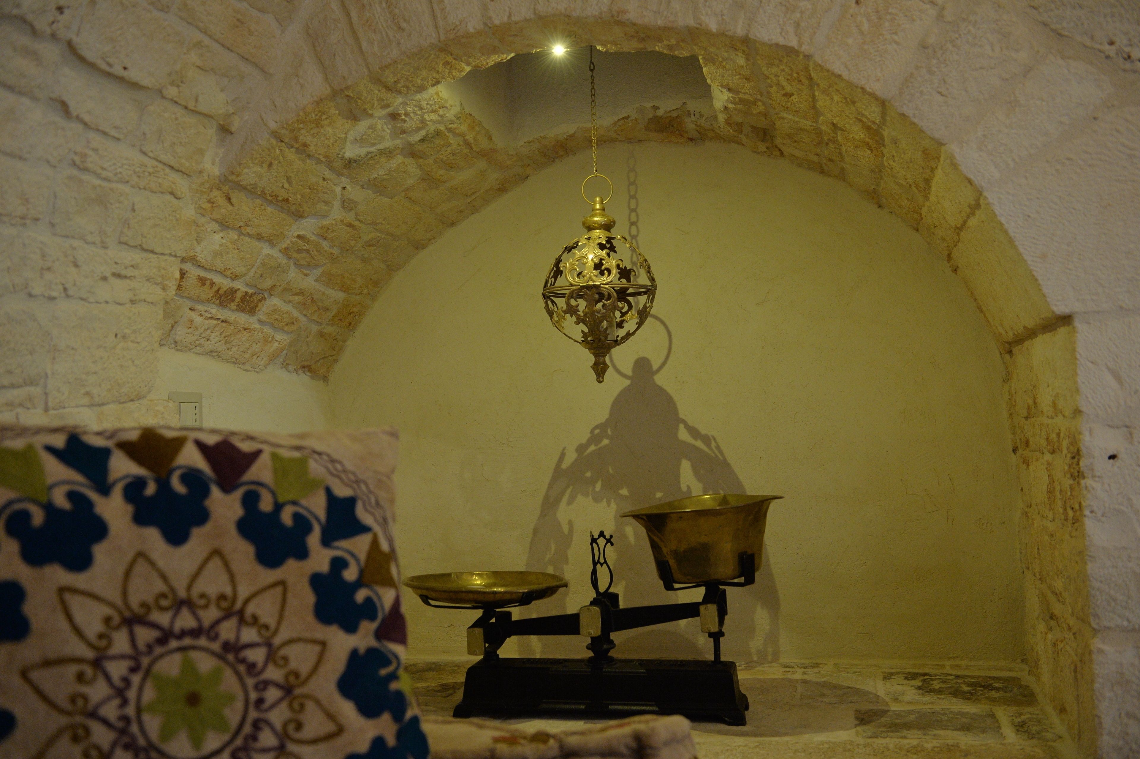 Una habitación con un arco de piedra, un farol colgante y una balanza.