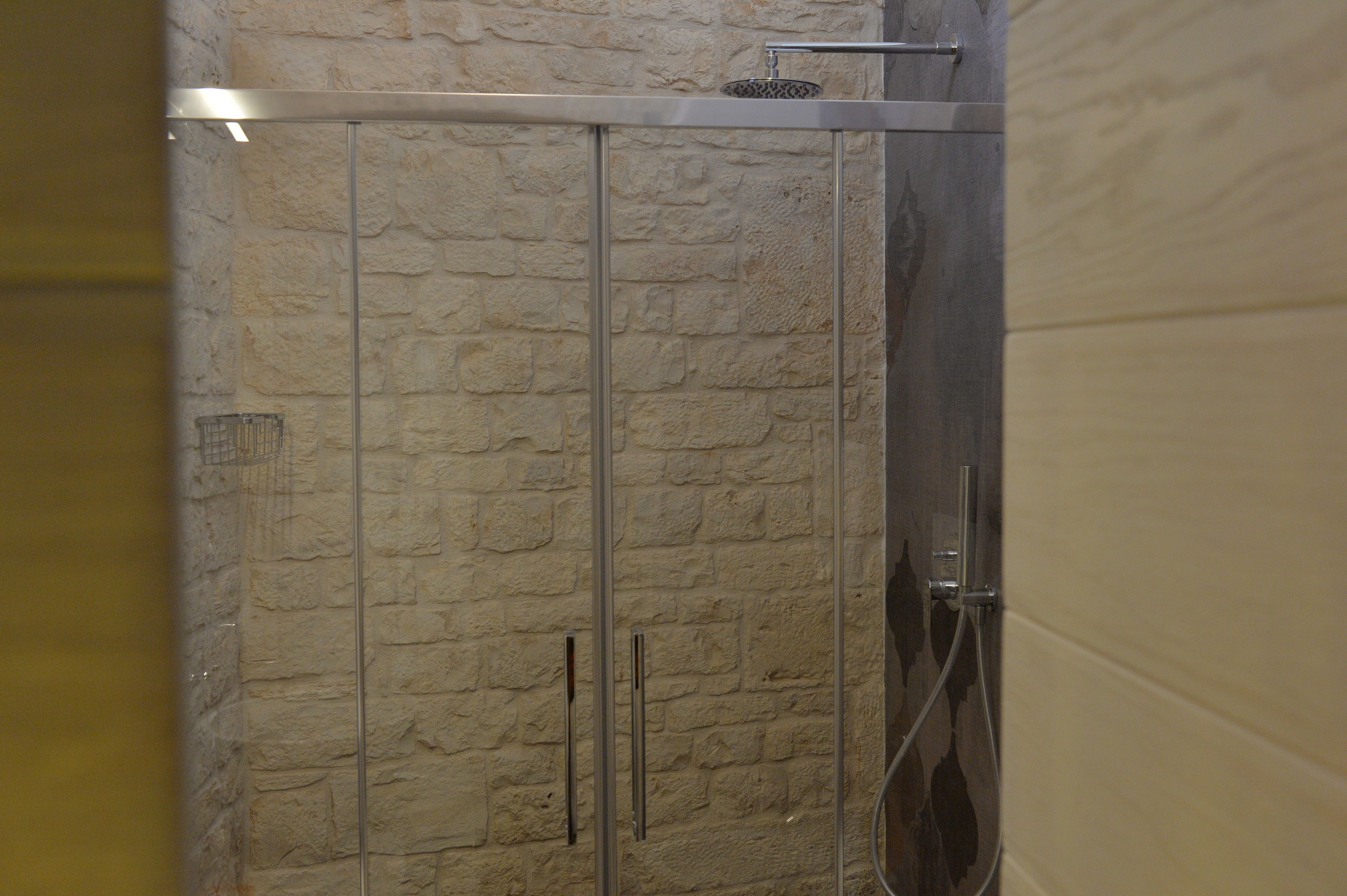A shower with a stone wall backdrop and a metal frame.