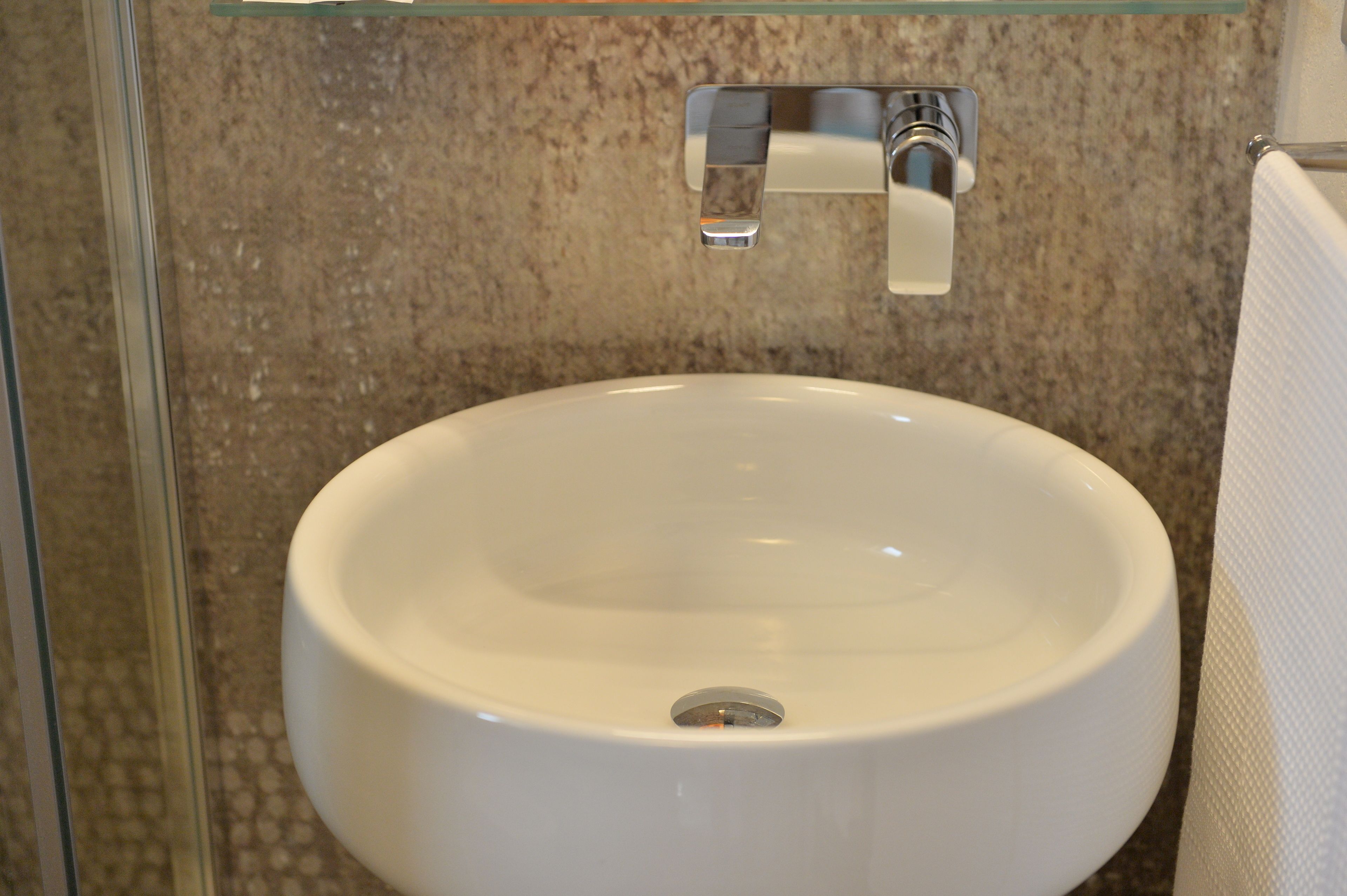 A bathroom with a white sink, a glass shower enclosure, and a granite countertop.