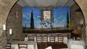 Un restaurant aux murs en briques, orné d’une fresque représentant un paysage, et doté de nombreuses tables et chaises.