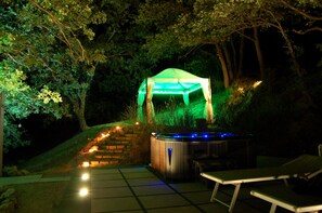 A hot tub and a covered seating area in a wooded outdoor setting. - Locanda dell' Angelo (Assisi)